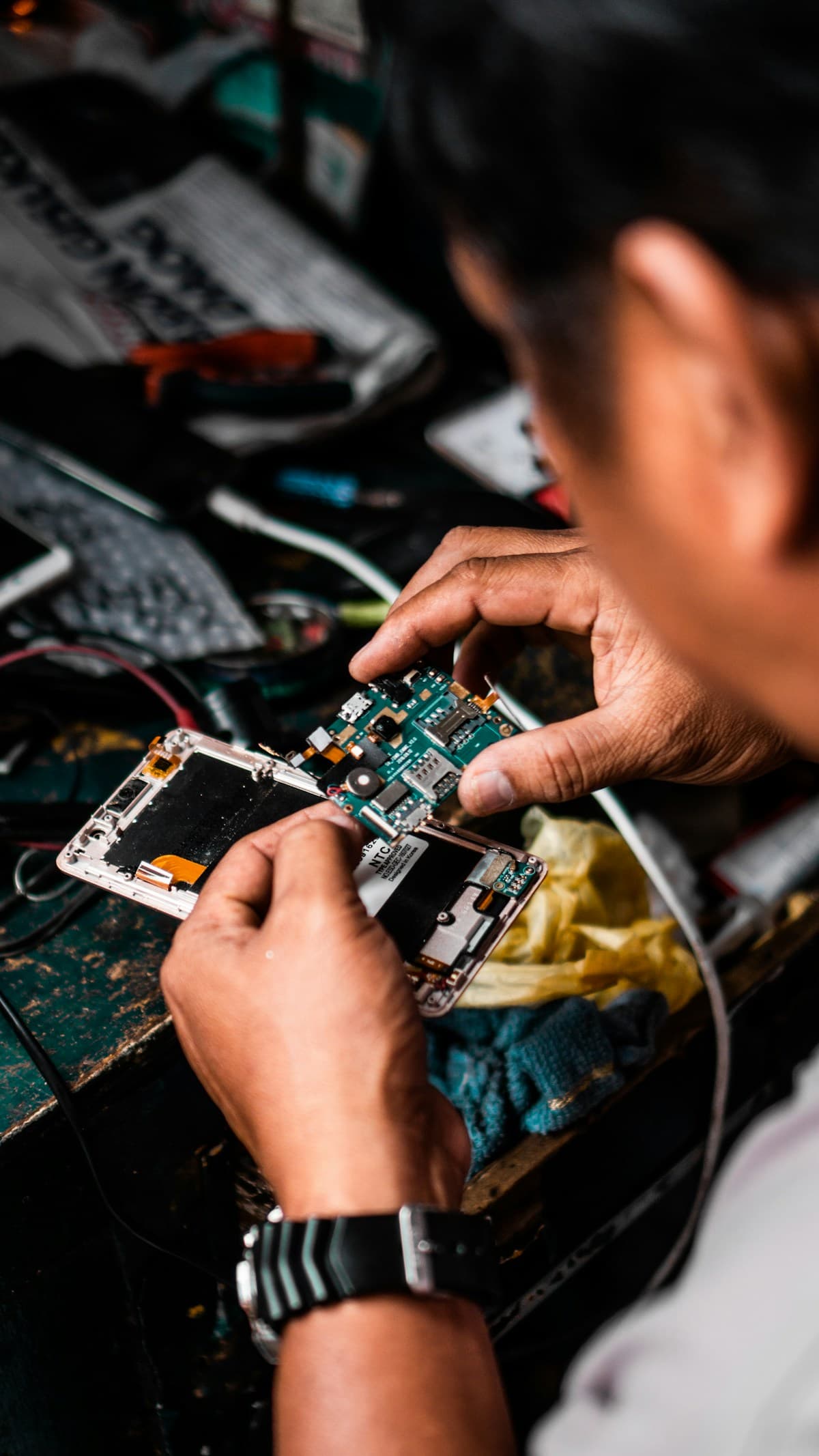 Techneut die met precisiegereedschap een smartphone-onderdeel repareert